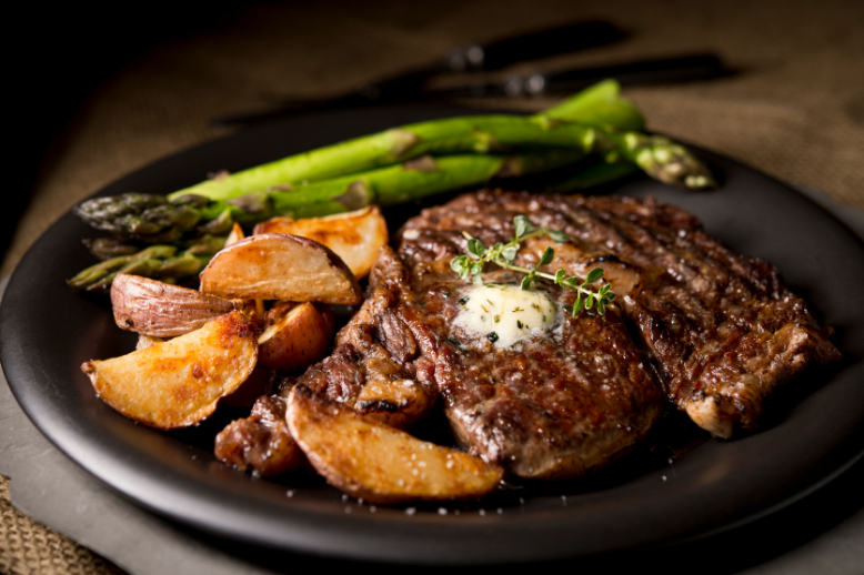 A steak with bacon pepper compound butter and asparagus