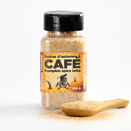 Bottle of pumpkin spice latte coffee spices with a wooden spoon on a white background
